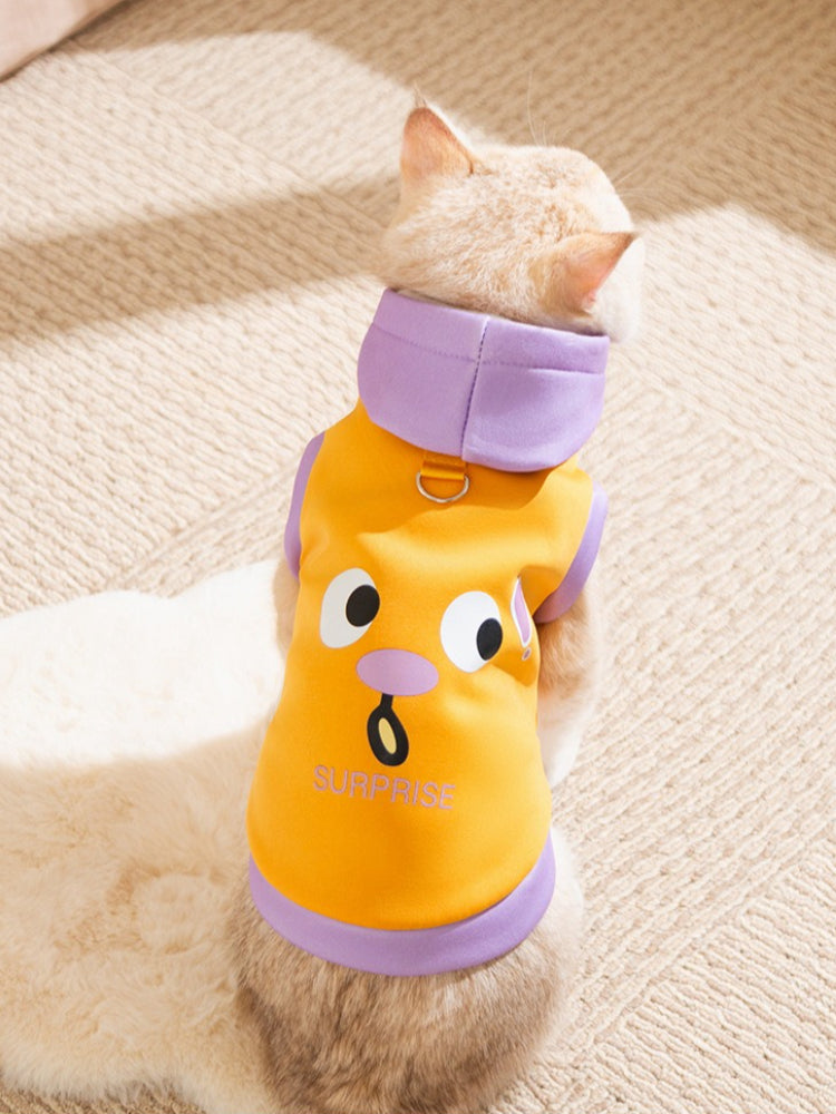 A cat wearing an orange hoodie with a surprised face graphic print and purple trim.