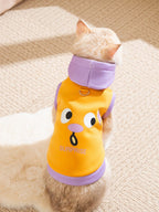 A cat wearing an orange hoodie with a surprised face graphic print and purple trim.