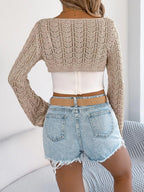 Back view of a woman wearing a beige cropped knit sweater with a white camisole and denim shorts