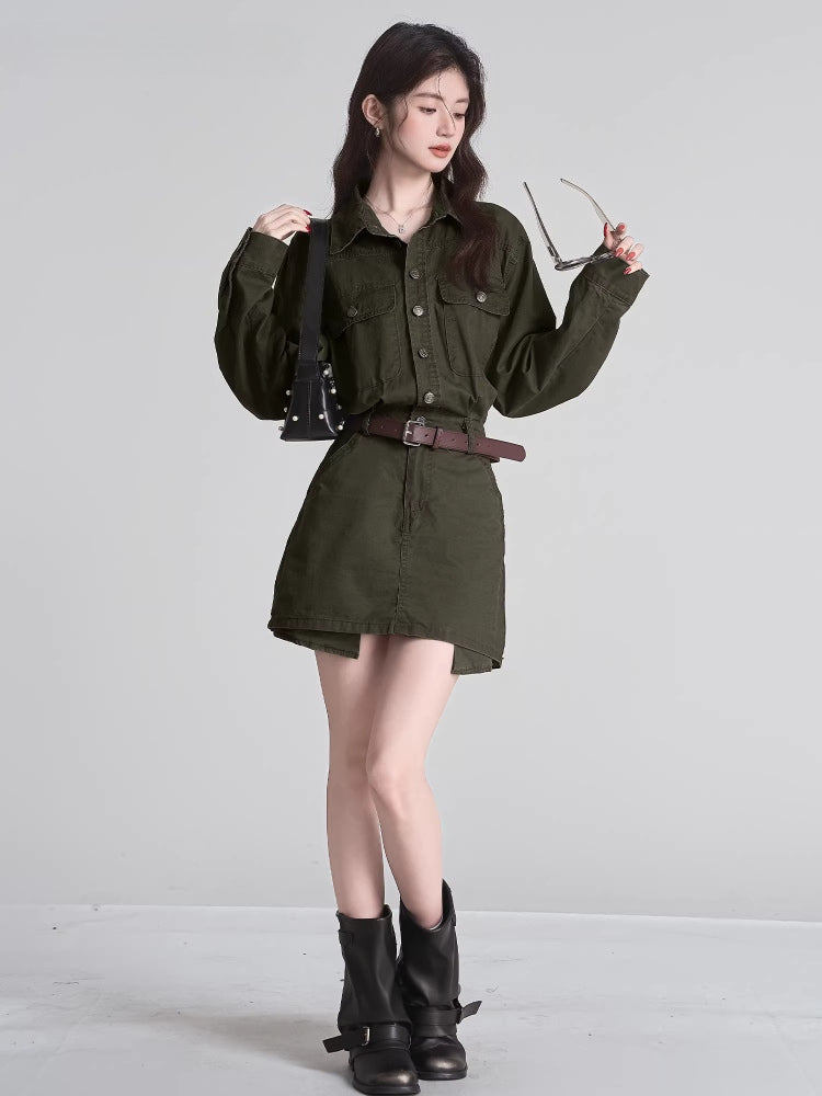 Full body shot of a woman in a green shirt and skirt set, wearing black boots and carrying a black handbag