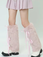 Full view of legs wearing pink faux fur leg warmers with ribbon ties, paired with a pink skirt and white shoes.
