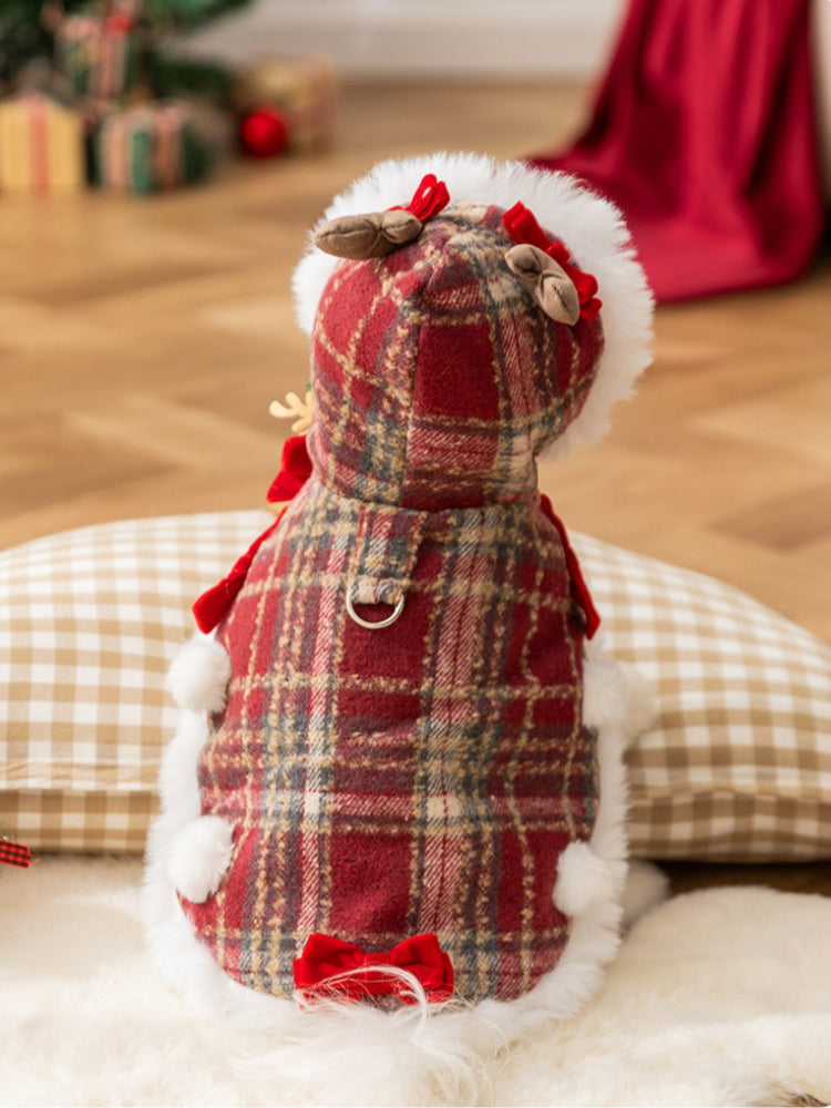 The rear view of a white bichon frise dog in a hooded red plaid dog coat with faux fur trim and festive embellishments.