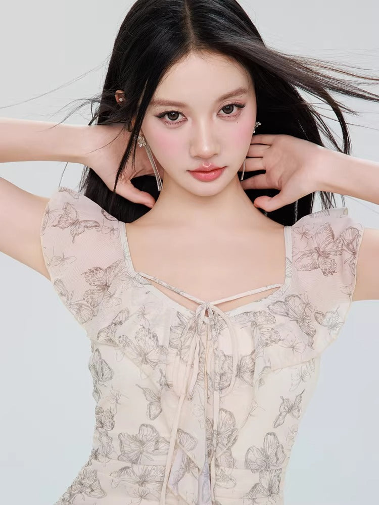 Close-up of the model's face and the neckline of the butterfly print dress, showing ruffled trim and tie detail.
