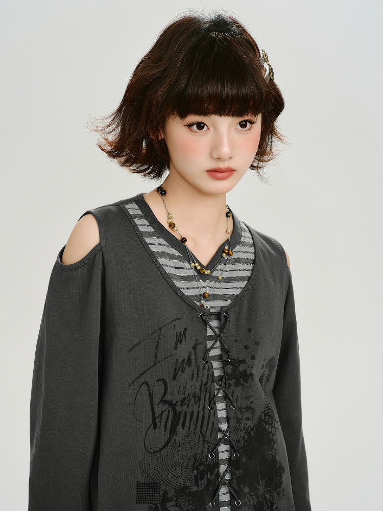 Close-up of the model's face and upper body, showcasing the layered grey top with graphic print and necklace.