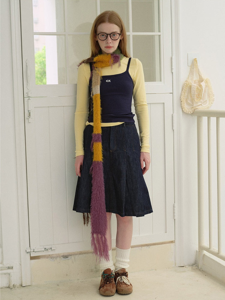 Full body shot of a woman standing in front of a white door, wearing a long striped scarf.