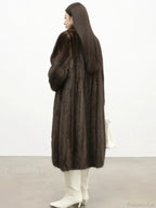 Back view of a woman in a brown mink fur coat and white boots.