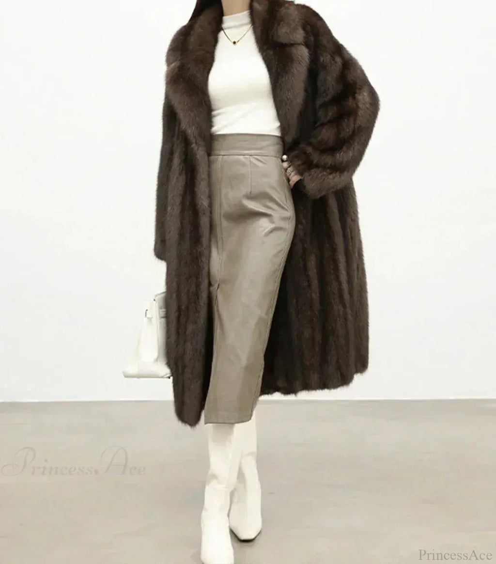 Woman wearing a brown mink fur coat, a white turtleneck, a grey leather skirt, and white boots, holding a white handbag.