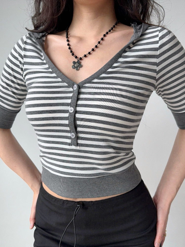 Close-up of a woman wearing a grey and white striped cropped top with a v-neck and button front.