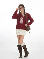 Woman adjusts her glasses while wearing a burgundy v-neck sweater with a white plaid detail, a white textured mini skirt, white knee-high socks, and brown buckled boots, carrying a brown crossbody bag.