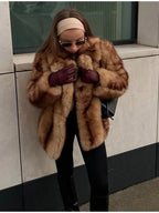Woman wearing a tan and brown faux fur cropped jacket with black pants and burgundy gloves, adjusting the jacket.