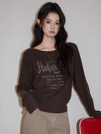 Close-up of a woman's brown long-sleeved graphic t-shirt.
