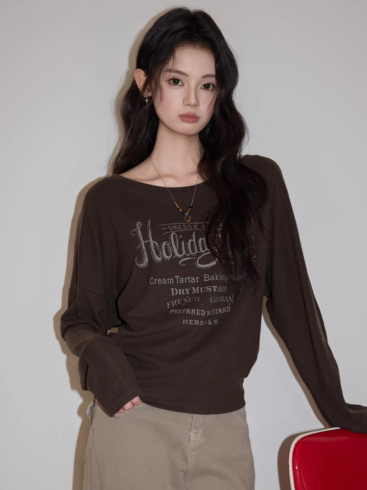 Close-up of a woman's brown long-sleeved graphic t-shirt.