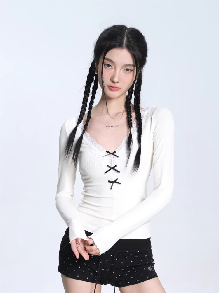 Model wearing a white ribbed long-sleeve top with lace trim and lace-up detail, paired with black shorts.