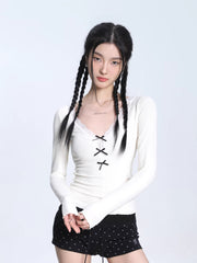 Model wearing a white ribbed long-sleeve top with lace trim and lace-up detail, paired with black shorts.
