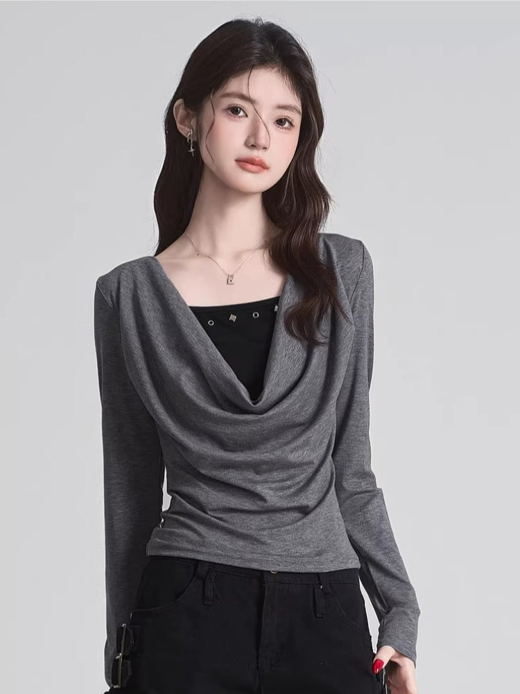 Woman wearing a grey draped long-sleeve top over a black camisole, paired with black pants.