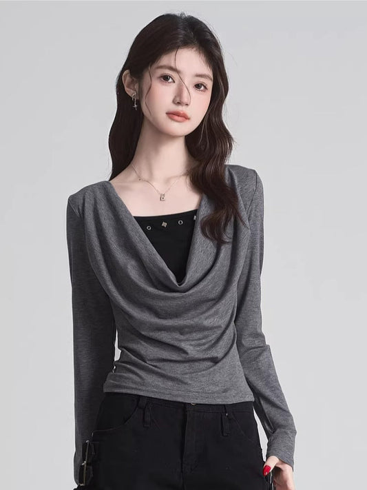 Woman wearing a grey draped long-sleeve top over a black camisole, paired with black pants.