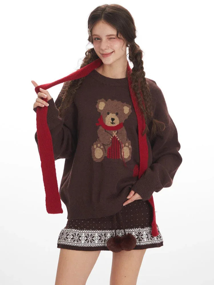 Woman winking and holding her red scarf while wearing a brown knit sweater with a teddy bear graphic