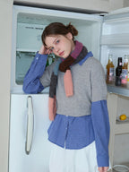 Model leaning against an open refrigerator, wearing a grey cropped sweater over a blue plaid long-sleeved shirt, white bubble skirt, and a colorful striped scarf.