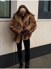 Woman wearing a tan and brown faux fur cropped jacket with black pants and burgundy gloves.