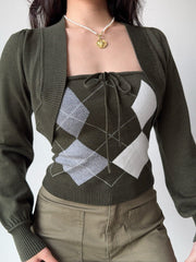 Front view of a woman wearing a two-piece knit set featuring a green argyle tube top and a matching cropped bolero cardigan.