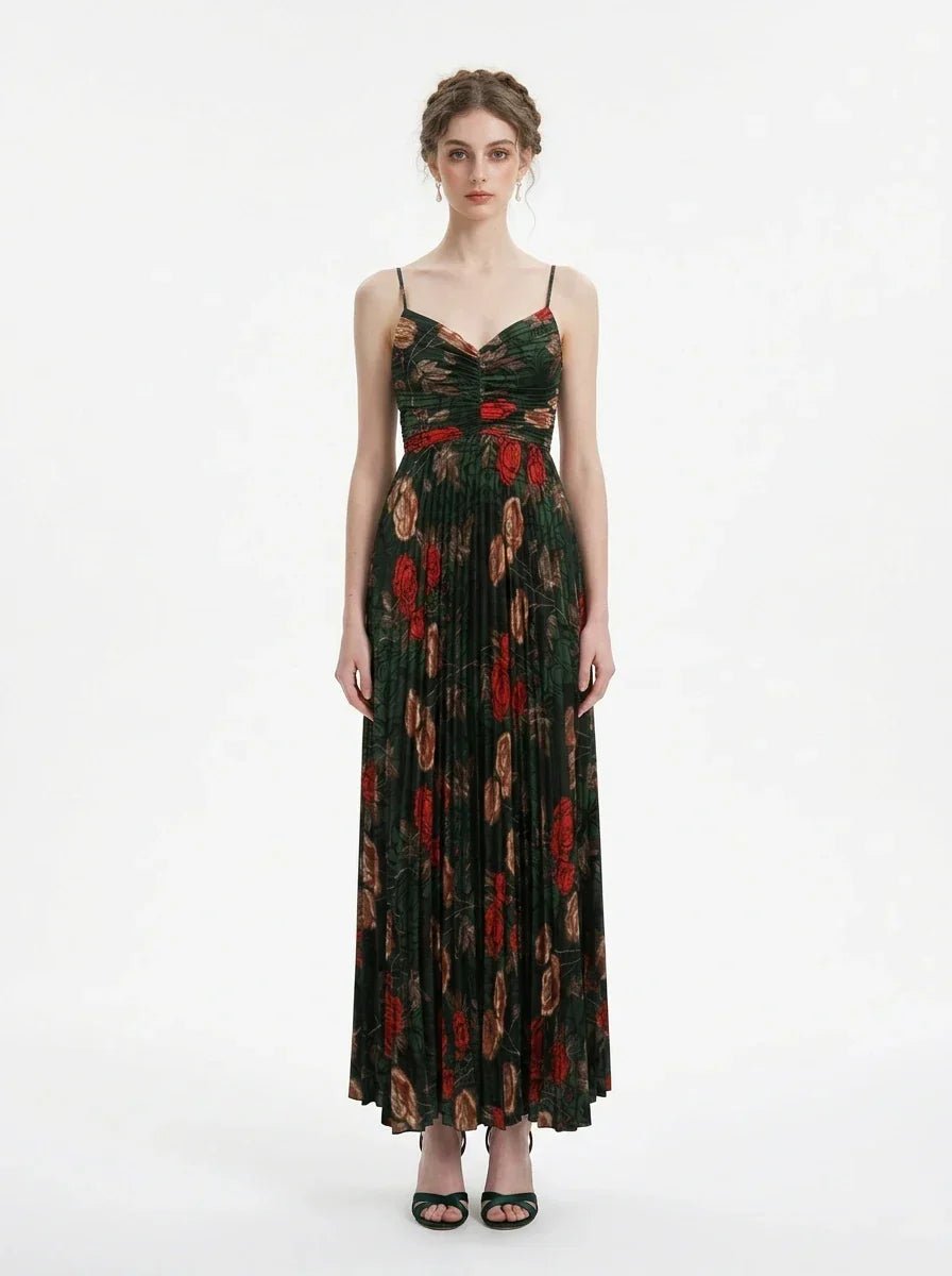 Woman wearing a dark green floral print maxi dress with spaghetti straps and a pleated skirt, front view.