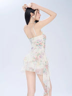 Back view of a woman in a floral print mini dress with spaghetti straps.