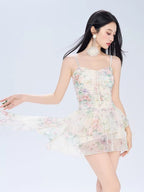 Woman posing in a flowing floral print mini dress with a ruffled hem.