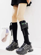 Person wearing black knee-high socks with a plush character accessory and black chunky sneakers.