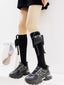 Person wearing black knee-high socks with a plush character accessory and black chunky sneakers.