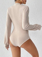 Back view of a woman wearing a cream-colored ribbed knit bodysuit with long sleeves and a mock neck.