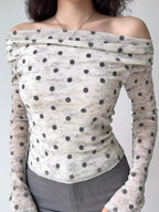 Front view of a woman in a white and grey polka dot off-the-shoulder mesh top