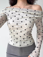 Close-up of a woman wearing a white and grey polka dot off-the-shoulder mesh top