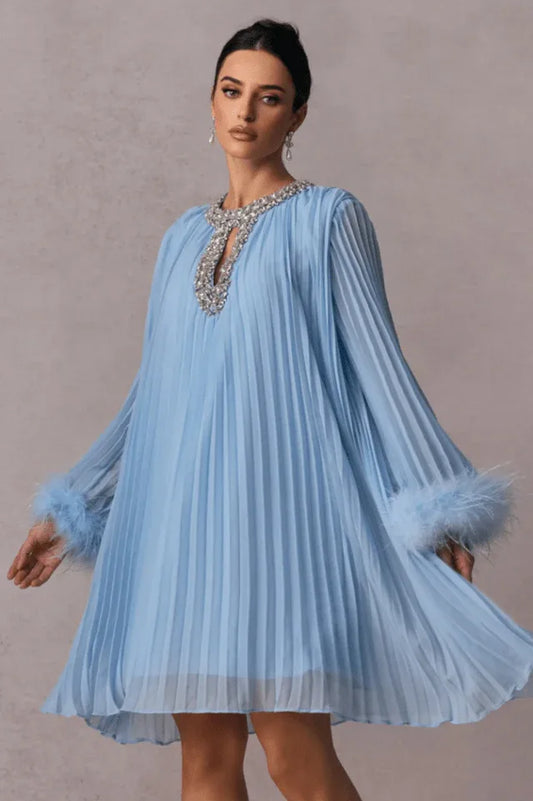 woman wearing a light blue pleated mini dress with feather cuffs and an embellished neckline