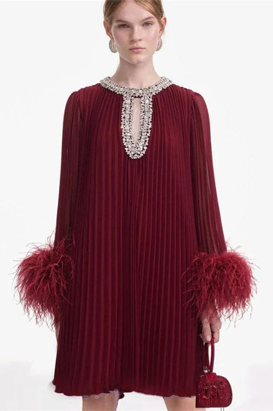 woman wearing a burgundy pleated mini dress with feather cuffs and an embellished neckline