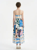 Full back view of a woman wearing a midi dress with an abstract geometric print and spaghetti straps.