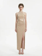 A woman models a shimmering champagne halter neck maxi dress with a cut-out and high slit.