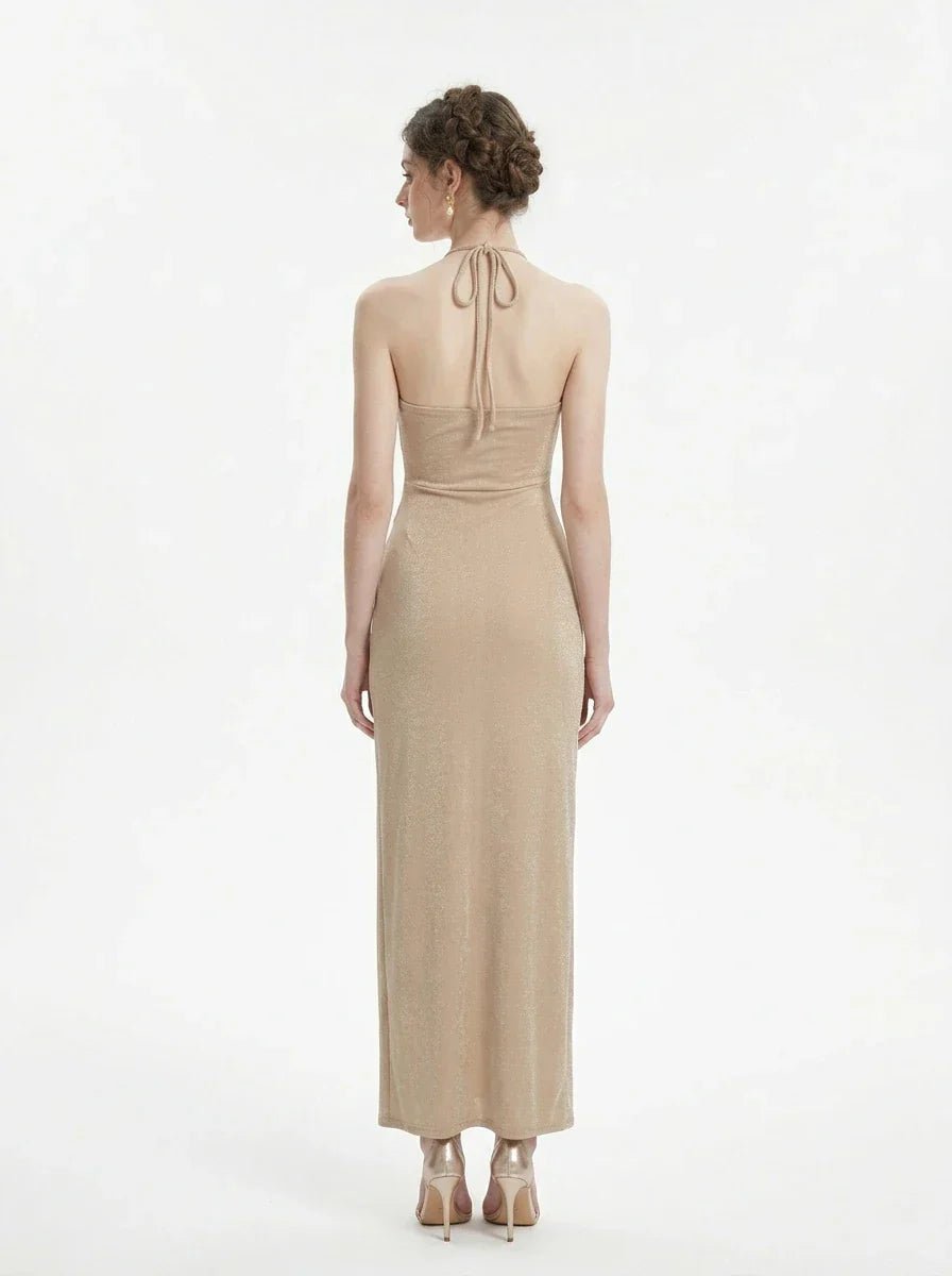 Back view of a woman in a champagne halter neck maxi dress with a shimmering finish.