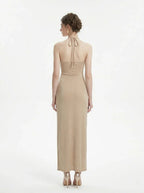 Back view of a woman in a champagne halter neck maxi dress with a shimmering finish.