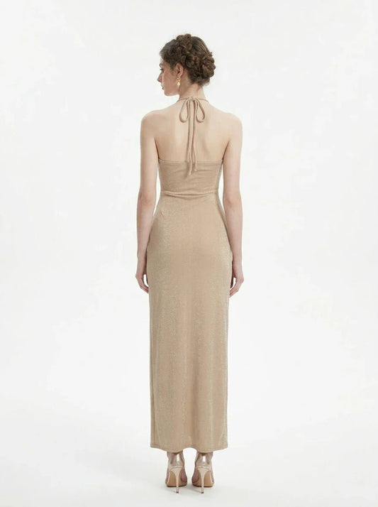 Back view of a woman in a champagne halter neck maxi dress with a shimmering finish.