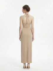 Back view of a woman in a champagne halter neck maxi dress with a shimmering finish.