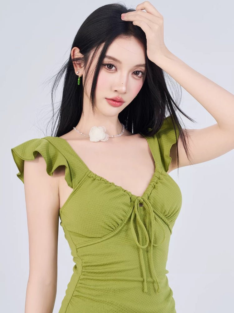 Close-up of the woman's face and the neckline of the green dress, showing ruffled details and a tie-front.