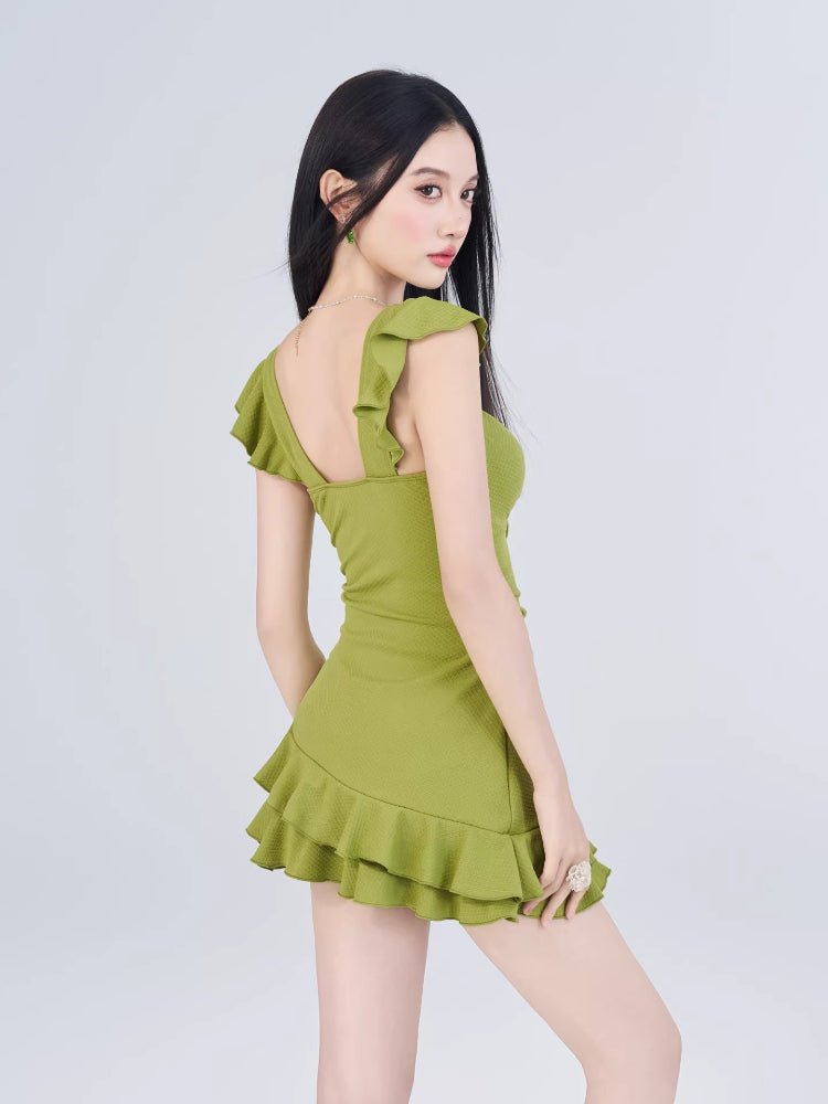 Rear view of the woman in the green dress, highlighting the ruffled cap sleeves and the back of the dress.