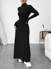Woman wearing a black ribbed knit maxi dress with a turtleneck and long sleeves, posing with hands on hips.