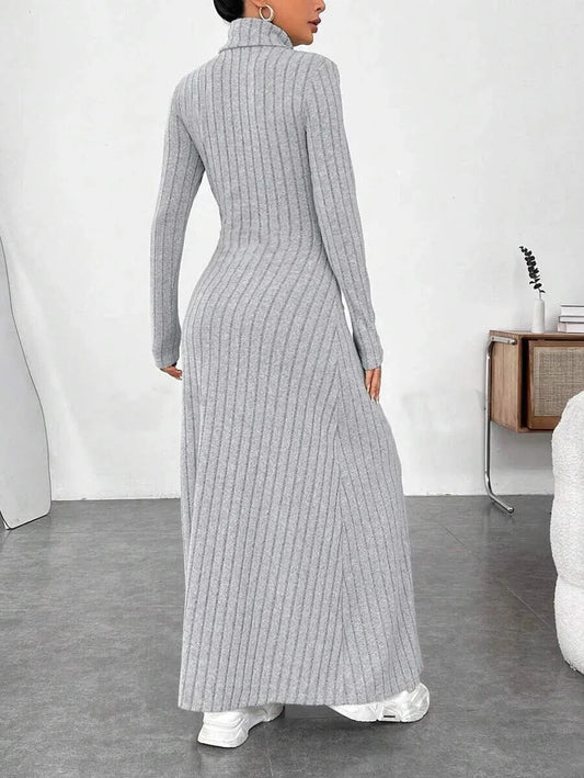 Back view of a woman wearing a grey ribbed knit maxi dress with a turtleneck and long sleeves.