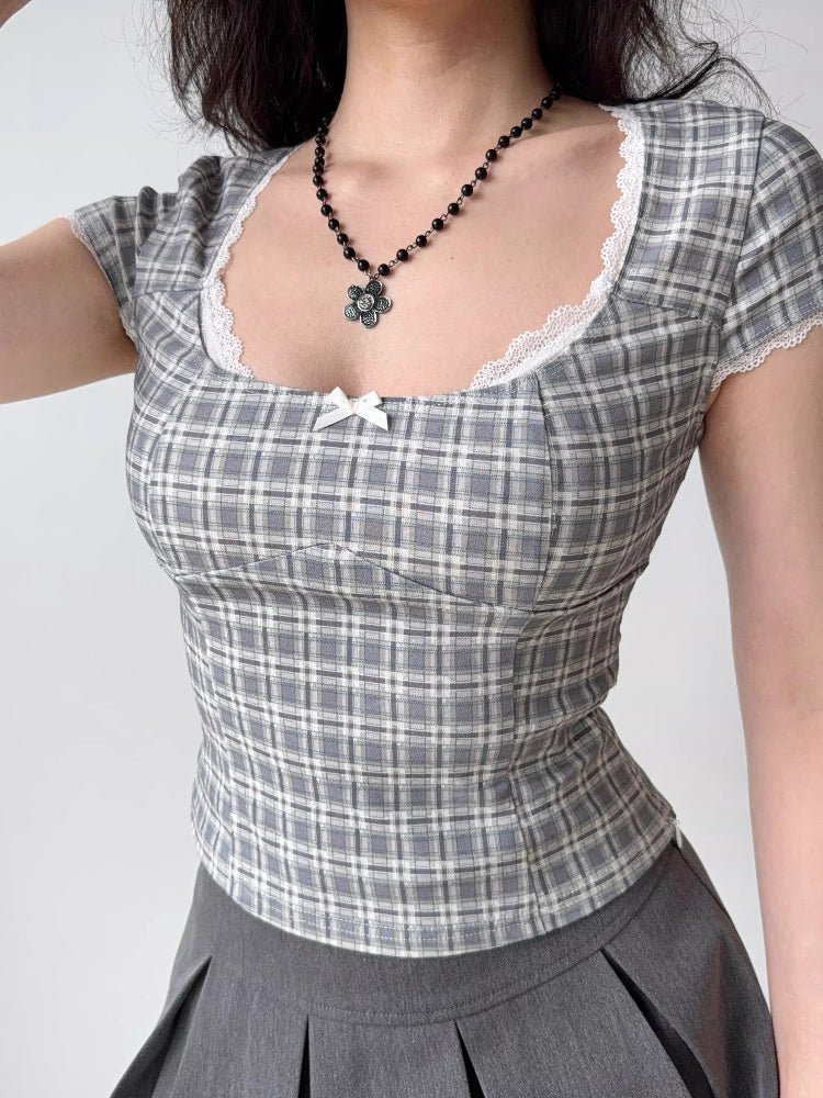 Woman wearing a gray plaid short-sleeved top with a sweetheart neckline and lace trim.
