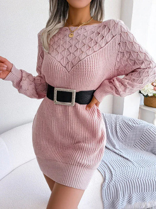 Woman wearing a pink knit sweater dress with an open knit yoke and sleeves, cinched with a black belt