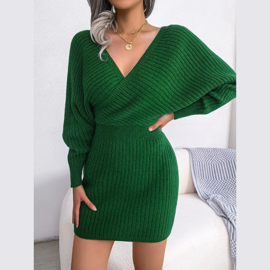 Woman wearing a green ribbed knit V-neck wrap mini dress with long dolman sleeves, standing with her hand on her hip.
