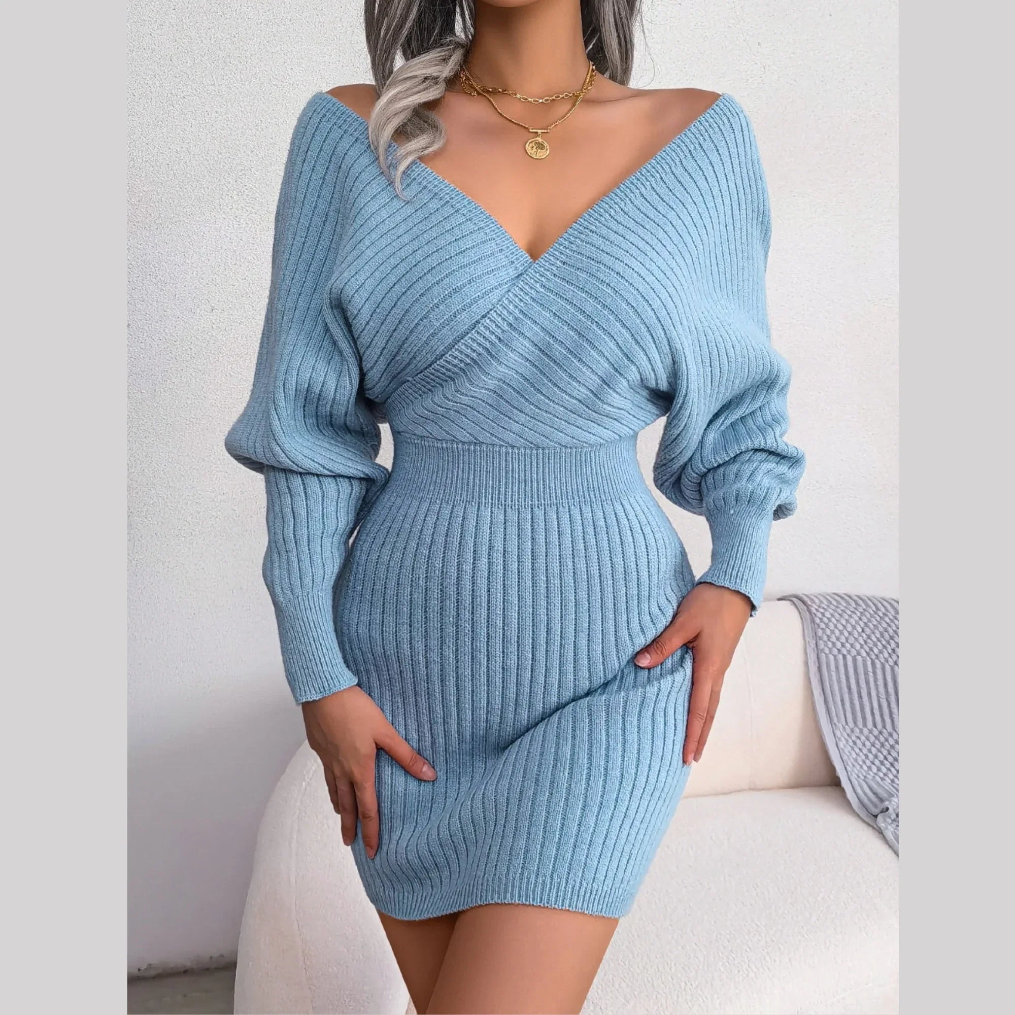 Woman wearing a light blue long-sleeved knit mini dress with a V-neckline and wrap front detail.