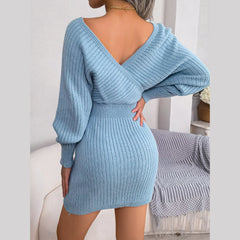 Back view of a woman in a light blue knit mini dress with a V-back and long sleeves.