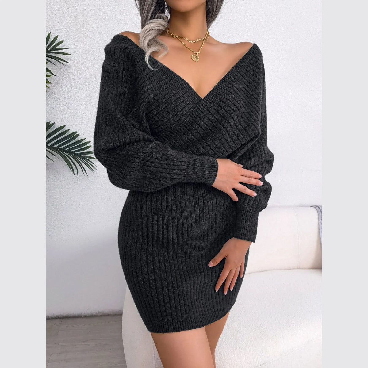 Woman wearing a charcoal ribbed knit V-neck mini dress with long sleeves and a wrap front.
